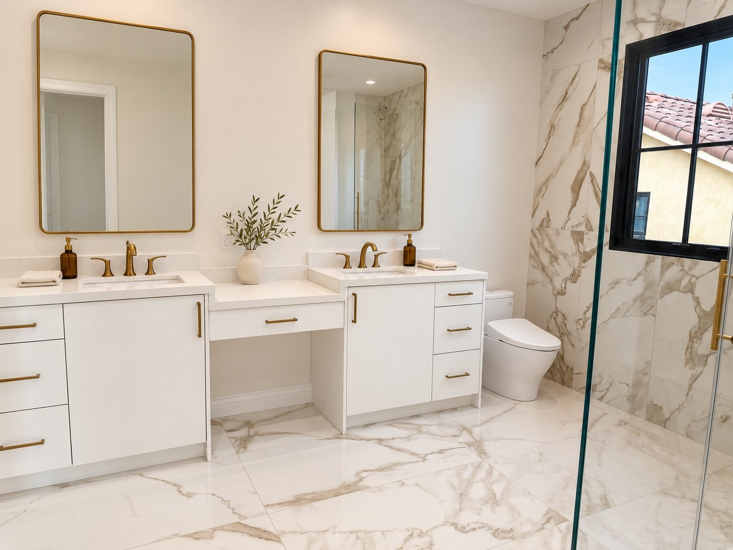 White bathroom vanity with makeup area and brass-framed mirrors