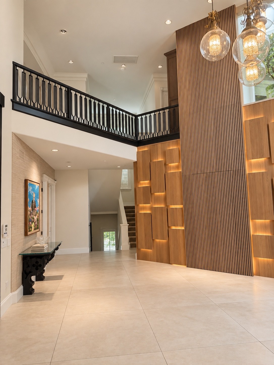 Foyer with illuminated wood panels and upper-level gallery