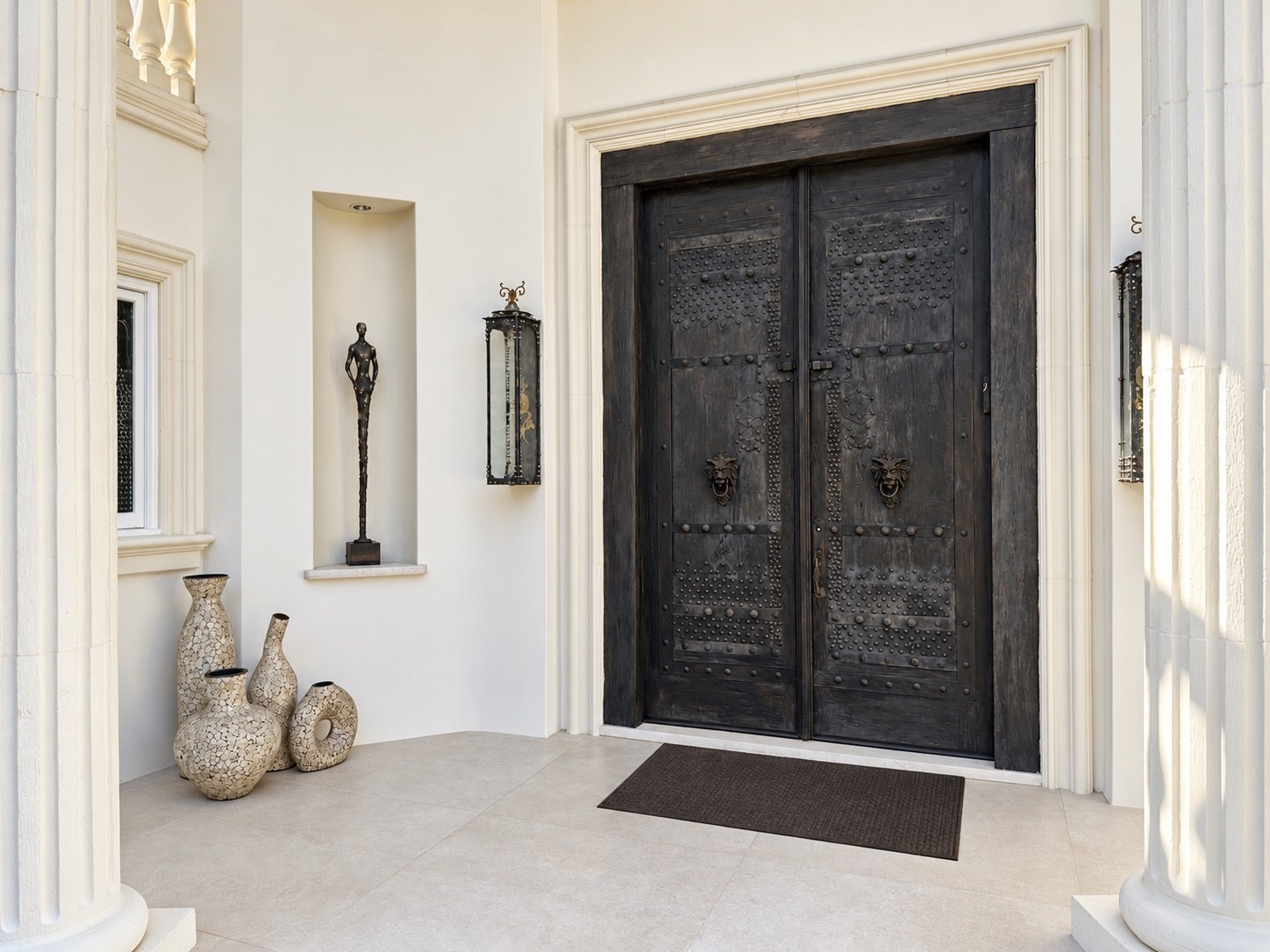 Entrance with dark carved doors and lantern sconces