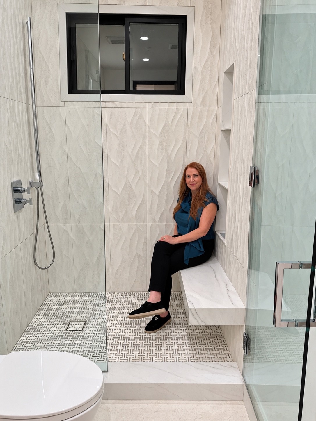Shower with textured wall tile and a built-in bench